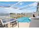 Screened-in pool area with outdoor dining, lounge chairs, and peaceful lake views beyond the enclosure at 157 Julliard Blvd, Davenport, FL 33897