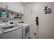 Well-organized laundry room with white washer, dryer, cabinets, shelving, and stylish wall décor at 1627 Mclucas Ln, The Villages, FL 34762