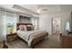 Bright main bedroom featuring a tray ceiling, ceiling fan, and two windows with natural light at 1627 Mclucas Ln, The Villages, FL 34762