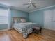 Comfortable bedroom features a ceiling fan, light blue walls, wood floors and a blue floral patterned bedspread at 1701 Lakewood Dr, The Villages, FL 32162