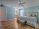 Comfortable bedroom features a ceiling fan, light blue walls, wood floors and a blue floral patterned bedspread at 1701 Lakewood Dr, The Villages, FL 32162