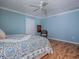 Comfortable bedroom features a ceiling fan, light blue walls, wood floors and a blue floral patterned bedspread at 1701 Lakewood Dr, The Villages, FL 32162