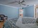 Comfortable bedroom features a ceiling fan, light blue walls, wood floors and a blue floral patterned bedspread at 1701 Lakewood Dr, The Villages, FL 32162