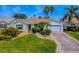 Charming single-story home with well-manicured lawn, lush landscaping, and a decorative driveway design at 1701 Lakewood Dr, The Villages, FL 32162