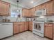 Well-lit kitchen showcasing wooden cabinets, modern appliances including microwave and stove, and tiled backsplash at 1701 Lakewood Dr, The Villages, FL 32162