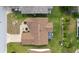 Aerial view of a house with a brown roof, screened in porch, and well-maintained lawn at 17068 Se 96Th Chapelwood Cir, The Villages, FL 32162