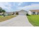 A home with a long driveway and a well-manicured front lawn at 17068 Se 96Th Chapelwood Cir, The Villages, FL 32162