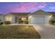 Charming single-story home featuring manicured landscaping and a two-car garage at sunset at 17068 Se 96Th Chapelwood Cir, The Villages, FL 32162