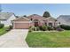 Single-story home with a well-kept lawn, garden, and a two car garage at 17108 Se 76Th Creekside Cir, The Villages, FL 32162