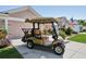 Tan Yamaha golf cart parked in front of a pink house with American flag at 17108 Se 76Th Creekside Cir, The Villages, FL 32162