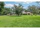 Vast backyard with lush lawn, mature trees, and screened pool enclosure at 1930 Country Club Rd, Eustis, FL 32726