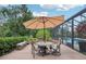 Covered patio area with seating, an umbrella, and a view of the screened-in pool at 1930 Country Club Rd, Eustis, FL 32726