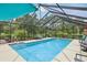 Inviting screened-in pool with lounge chairs, lush landscaping, and clear blue water at 1930 Country Club Rd, Eustis, FL 32726