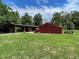 Exterior view of a red barn with an open barn and green grassy area at 19703 Lake Lincoln Ln, Eustis, FL 32736