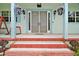 Inviting front porch with decorative pillars, hanging floral baskets, and red brick steps at 19703 Lake Lincoln Ln, Eustis, FL 32736