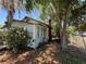 Exterior view of a quaint home needing repair, surrounded by foliage and a chain-link fence, offering a renovation opportunity at 2001 Bates Ave, Eustis, FL 32726