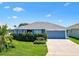 Charming single-story home featuring a two-car garage and well-manicured front lawn under a blue sky at 2160 Biller Cir, The Villages, FL 32163