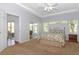 Bright bedroom features neutral carpet, a queen bed with floral bedding, and access to the sunroom at 21926 King Alfred St, Leesburg, FL 34748
