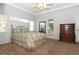 Bright bedroom features neutral carpet, a queen bed with floral bedding, and views to the Primary bath at 21926 King Alfred St, Leesburg, FL 34748