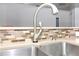 Close-up of a stainless steel kitchen sink with a modern faucet and multicolored backsplash tiles at 21926 King Alfred St, Leesburg, FL 34748