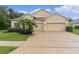 Charming home with a two-car garage, lush landscaping, and well-maintained lawn at 2424 Plumadore Dr, Grand Island, FL 32735