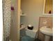 Compact bathroom featuring a tiled shower, toilet with shelving, pedestal sink and neutral color scheme at 2501 Sheridan Rd, Mount Dora, FL 32757