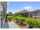 Backyard features a sidewalk and green shrubs lining mulch beds at 2568 Jupiter Way, The Villages, FL 32163