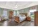 This primary bedroom suite features wood floors, natural light, and an armchair at 2568 Jupiter Way, The Villages, FL 32163