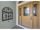 Elegant front door featuring decorative glass panels, modern hardware, and adjacent decorative wall art at 2568 Jupiter Way, The Villages, FL 32163