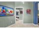 Hallway with neutral paint leads to bedroom with natural light and artistic wall decor at 2568 Jupiter Way, The Villages, FL 32163