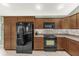 Well-lit kitchen boasts wooden cabinetry, stainless steel appliances, and tile backsplash at 2568 Jupiter Way, The Villages, FL 32163