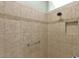 An updated shower features tile surround with a decorative band, shower niche and grab bar at 2568 Jupiter Way, The Villages, FL 32163