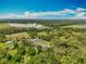 Overhead shot featuring a home, swimming pool, and surrounding trees with a factory in the background at 27610 Debbie Rd, Okahumpka, FL 34762