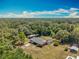 Aerial view of a home with a screened-in pool surrounded by lush greenery and a detached garage at 27610 Debbie Rd, Okahumpka, FL 34762