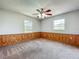 Bedroom with paneling, ceiling fan, carpeted floors, and two windows for natural light at 27610 Debbie Rd, Okahumpka, FL 34762