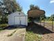 View of white barn-style garage with car port, a fenced yard, and concrete driveway at 27610 Debbie Rd, Okahumpka, FL 34762