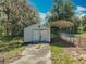 Storage shed and carport surrounded by lush trees and a lush natural landscape at 27610 Debbie Rd, Okahumpka, FL 34762
