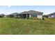 View of the backyard showcasing a well-maintained lawn, manicured landscaping, and a partially screened patio at 2988 Sentell St, The Villages, FL 32163