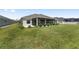 View of the backyard showcasing a well-maintained lawn, manicured landscaping, and a partially screened patio at 2988 Sentell St, The Villages, FL 32163