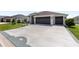 Wide driveway leading to a two-car garage, complemented by a well-manicured lawn and decorative landscaping at 2988 Sentell St, The Villages, FL 32163