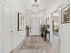 Bright entryway with neutral colors, wood-look floors, decorative plants, and artwork leading to the living space at 2988 Sentell St, The Villages, FL 32163