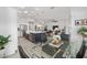 Open-concept kitchen with stainless steel appliances, island with seating, and dining area with a glass table at 2988 Sentell St, The Villages, FL 32163