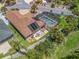 Aerial view of a home featuring a solar-paneled roof, a screened-in pool, and a patio area surrounded by lush greenery at 2998 Kramer Ct, The Villages, FL 32163