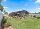 Wide backyard view featuring a large screened-in pool enclosure, patio furniture, and mature landscaping at 2998 Kramer Ct, The Villages, FL 32163