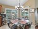 Cozy dining area features a glass table, chandelier, and sliding door to the outdoor patio with pool views at 2998 Kramer Ct, The Villages, FL 32163