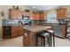 Well-equipped kitchen with stainless steel appliances, granite countertops, island with stools, and tile backsplash at 2998 Kramer Ct, The Villages, FL 32163