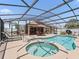 Aerial view of the screened pool area with spa, lounge chairs, and outdoor dining space at 2998 Kramer Ct, The Villages, FL 32163