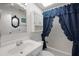 Clean bathroom with a shower with a blue curtain and sink and a vanity with a mirror at 32335 Oak Park Dr, Leesburg, FL 34748