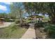 A backyard patio with a charming pergola dining area surrounded by lush landscaping and inviting walkways at 397 Anderson Dr, Tavares, FL 32778