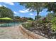 Beautifully landscaped backyard featuring a pool with a safety fence and rock features at 397 Anderson Dr, Tavares, FL 32778